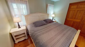 Une chambre à coucher avec un lit, des tables de chevet et une armoire en bois.