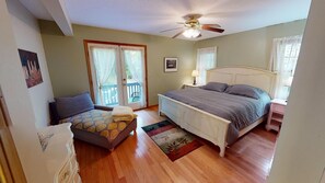 A bedroom with a bed, a chair, a dresser, and a balcony door.