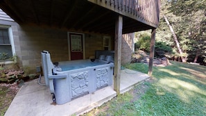 A stone hot tub with a wooden deck, a brick wall, and a door. - Brookside Cottage In Hocking Hills (Rockbridge)