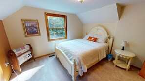 A bedroom with a bed, a window, a lamp, and a quilted chair. - Brookside Cottage In Hocking Hills (Rockbridge)