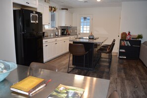 A compact kitchen with a black refrigerator, white cabinets, and a small island with bar stools. - Meadow Lane In Hocking Hills (Logan)