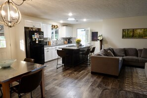 A modern kitchen with white cabinets, a black refrigerator, and a dining area with a glass table and chairs.