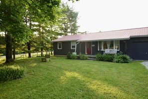 A single-story house with a red roof, a porch with a red door, and a sign that reads "Home."