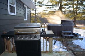 A backyard with a barbecue grill, a hot tub, and a wooden deck. - Meadow Lane In Hocking Hills (Logan)