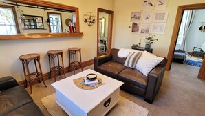 Ein Wohnzimmer mit einem braunen Ledersofa, einem weißen Couchtisch und drei Holzhocker.