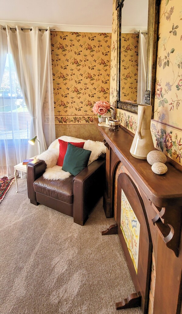 A cozy room with a brown leather sofa, a small table with a lamp, and a mirror.