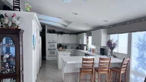 Una cocina moderna con armarios blancos, una isla central y un comedor con sillas de madera.