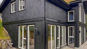 A two-story building with large windows and a dark exterior. - Cozy home in Hovden i Setesdal - with jacuzzi (Hovden i Setesdal)
