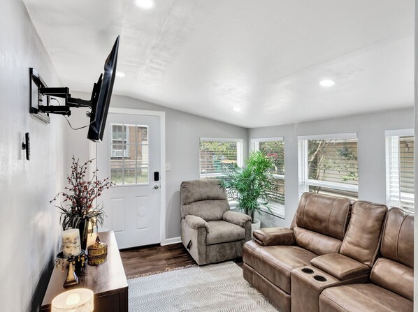 A modern living room with a grey sofa, a beige armchair, and a television mounted on the wall.