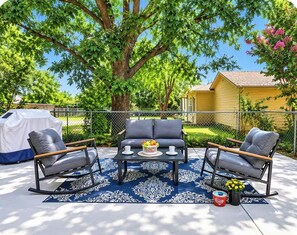 An outdoor patio with a dining set, a covered grill, and a yellow house in the background. - Spacious 5BR Corporate Home/Ideal for Work Crews & Long Stays/Centrally located (Sherman)
