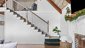 A staircase with wooden railings and a white wall with a herringbone pattern.