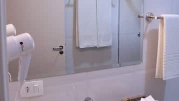 A bathroom with a sink, a hairdryer, a mirror, and a towel rack.
