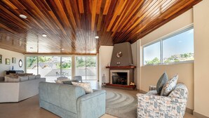 A living room with a fireplace, two sofas, a rug, and a view through large windows.