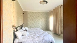 A bedroom with a bed, curtains, and a patterned wall.