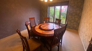 A dining area with a round wooden table, six chairs, and a chandelier.