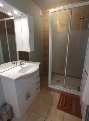 Une salle de bain moderne avec un meuble-lavabo blanc, une douche en verre et un plancher en bois.
