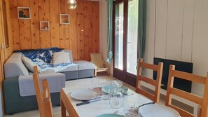 A cozy room with a wooden interior, a sofa, a dining table set with plates and glasses, and a chair.