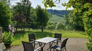 Un espace extérieur aménagé avec une table et des chaises, entouré d’arbres et offrant une vue sur un paysage verdoyant.