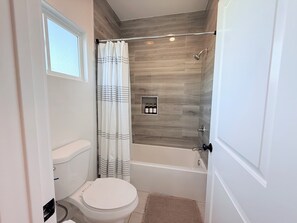 Een badkamer met een toilet, een douche en een bad.