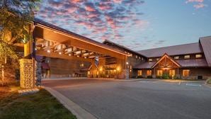 A lodge with a covered entrance, stone pillars, and a parking lot.