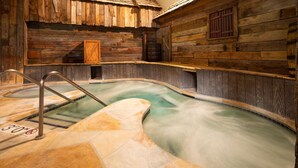 A wooden spa with a stone pool and a metal ladder.
