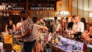 A bar area with a bartender preparing drinks, shelves with various bottles, and a counter with multiple drink dispensers.