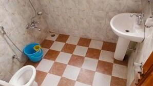 Un baño con piso a cuadros, un inodoro, un lavamanos y una ducha.