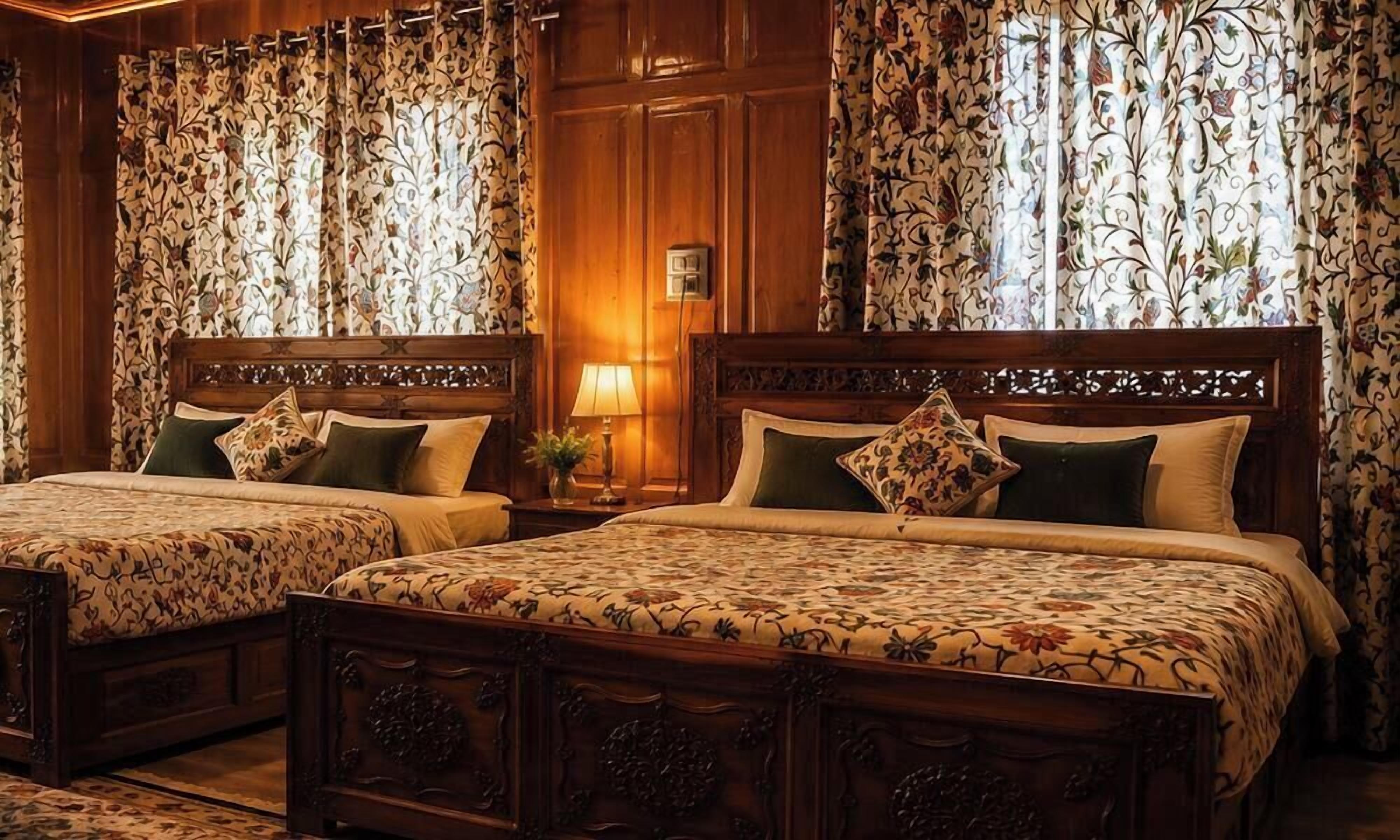A hotel room with two wooden beds, floral-patterned bedding, and curtains with a floral design.