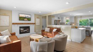 A spacious living room with a fireplace, a kitchen area, and a dining space.