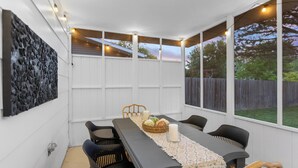 A covered patio with a dining table, chairs, and a decorative wall.