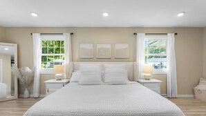 A spacious bedroom with a large bed, two bedside tables with lamps, and three framed pictures on the wall.