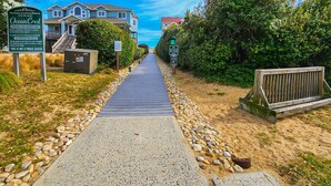 Une promenade privée en bord de mer, avec une jetée en bois, entourée de maisons et d’une végétation luxuriante.