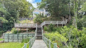 Un sendero de madera que conduce a una casa con escaleras y una terraza de madera.