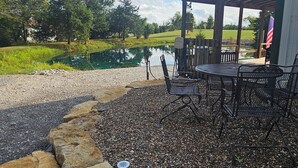 Un espace patio agrémenté d’une pergola, de sièges d’extérieur et offrant une vue sur un étang.