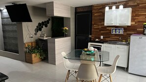 Een moderne keuken met een ingebouwde oven, een witte koelkast en houten wandpanelen.