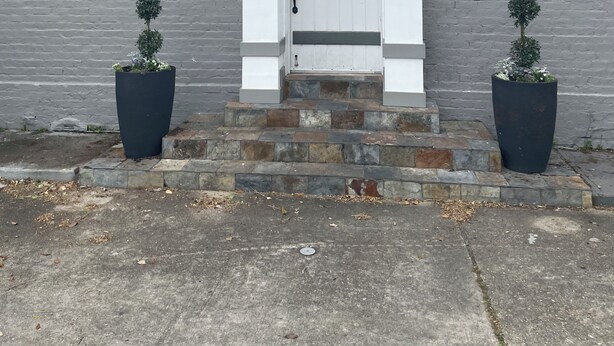 A grey brick building with a white door, a small window above the door, and two potted plants on either side of the door. - Fully furnished. we provide all utilities wifi and gated parking. pet friendly (New Orleans)