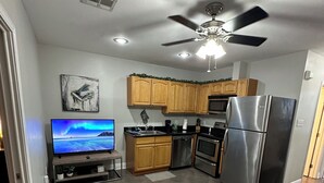 A modern kitchen with wooden cabinets, a stainless steel refrigerator, and a ceiling fan. - Fully furnished. we provide all utilities wifi and gated parking. pet friendly (New Orleans)
