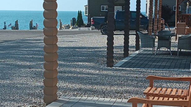 Een overdekt buitengebied met een houten bank, een pergola en uitzicht op zee.