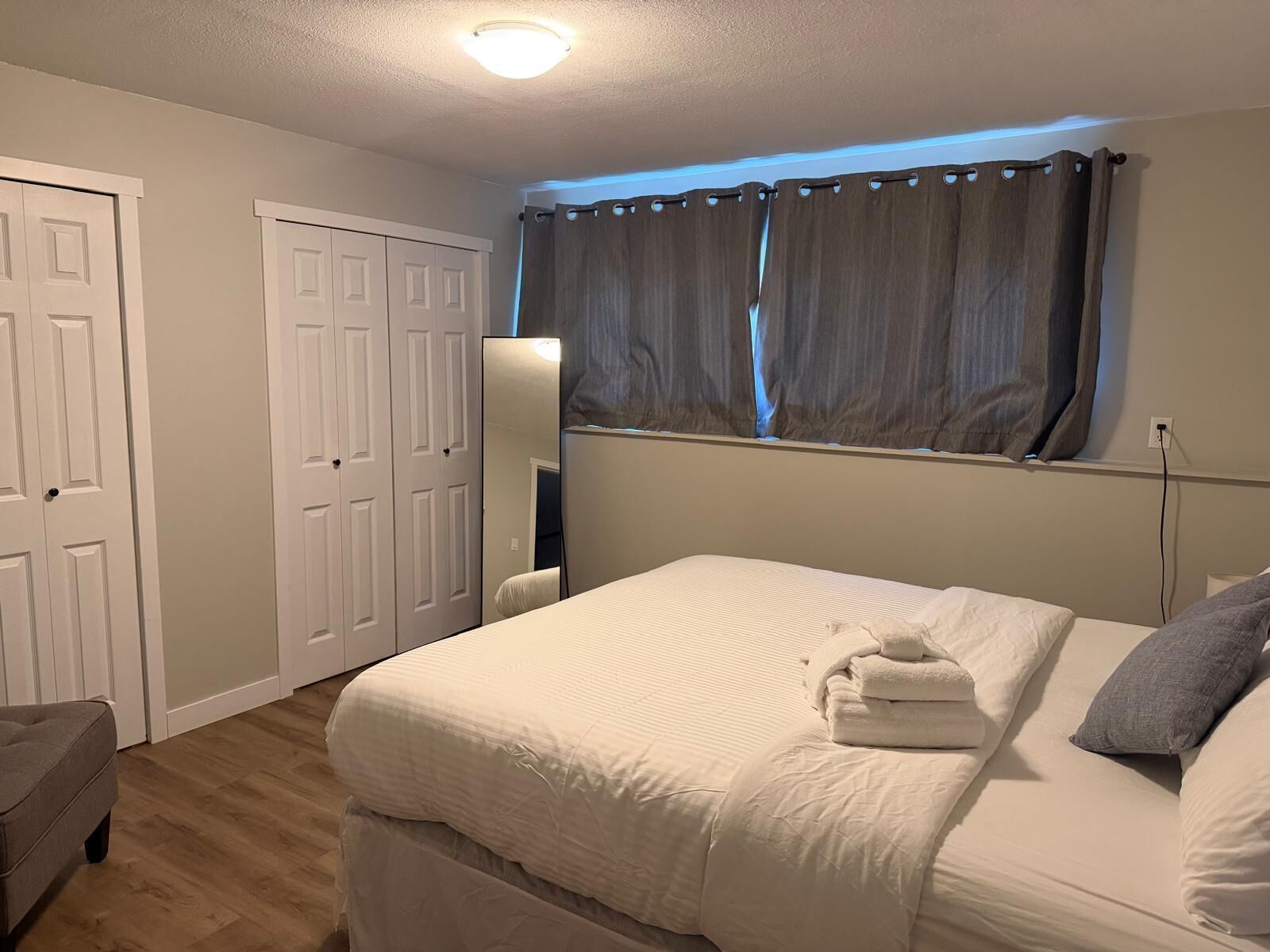 A bedroom with a bed, a nightstand, a lamp, and a window with curtains.