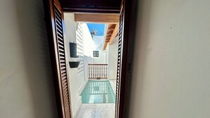 Un corridoio stretto che conduce a una zona piscina con vista su un edificio e un cielo sereno.