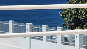 Una vista di un balcone con ringhiere bianche che si affaccia su un corpo d'acqua e un albero.