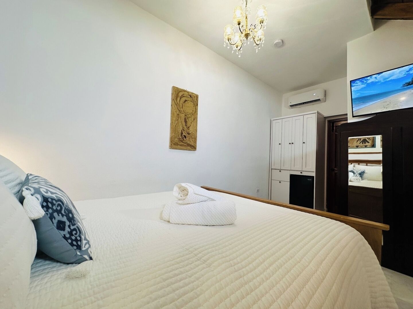 Una camera da letto con un letto, un lampadario, un quadro, un armadio e una televisione.
