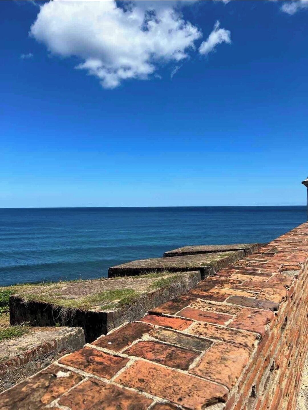 A coastal view with a stone wall and the ocean.