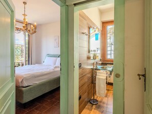 A bedroom with a bed, a chandelier, and a view of the outside.