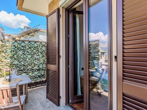 A balcony with a wooden table, a glass door, and a wall covered in foliage.