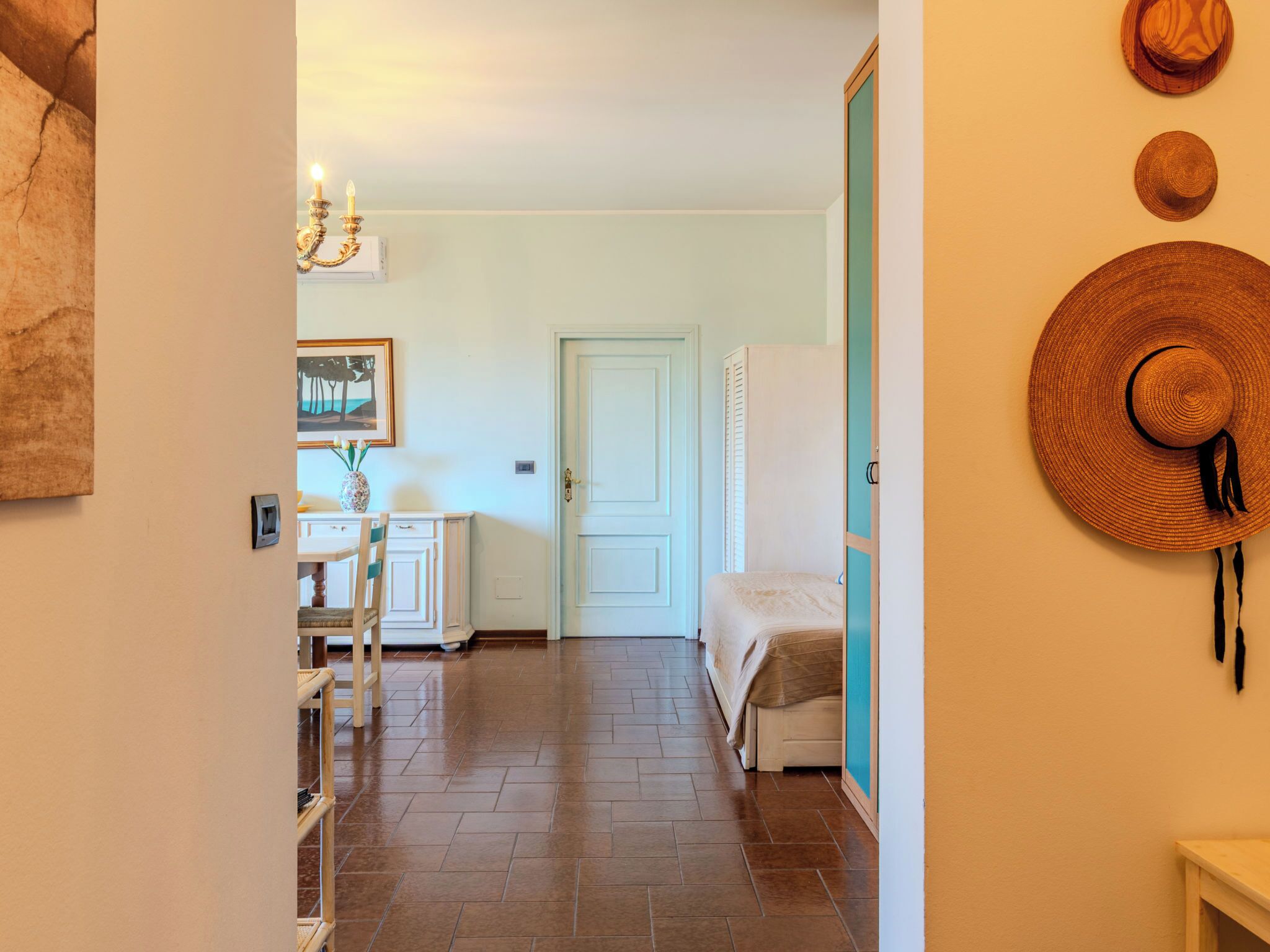 A hallway with a bed, a door, and a wall-mounted hat.