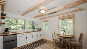 Una cocina moderna con armarios blancos, lavavajillas integrado y una zona de comedor con mesa y sillas de madera.