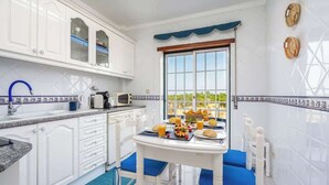 Una cucina con mobili bianchi, un tavolo da pranzo con sedie blu e una colazione servita.
