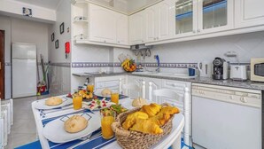 Una cucina con mobili bianchi, un forno a microonde, una macchina da caffè e una colazione servita sul bancone.