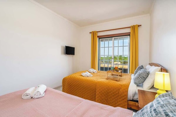 Una habitación de hotel con dos camas, un televisor y una ventana con cortinas.